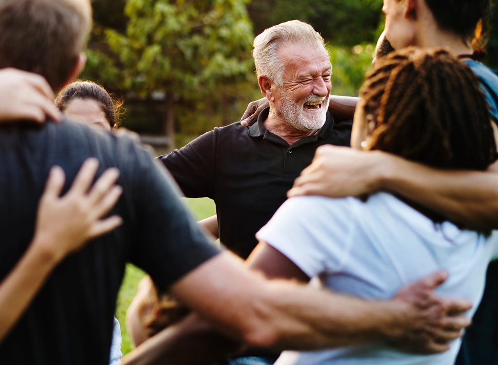 Smiling older man surrounded by community members